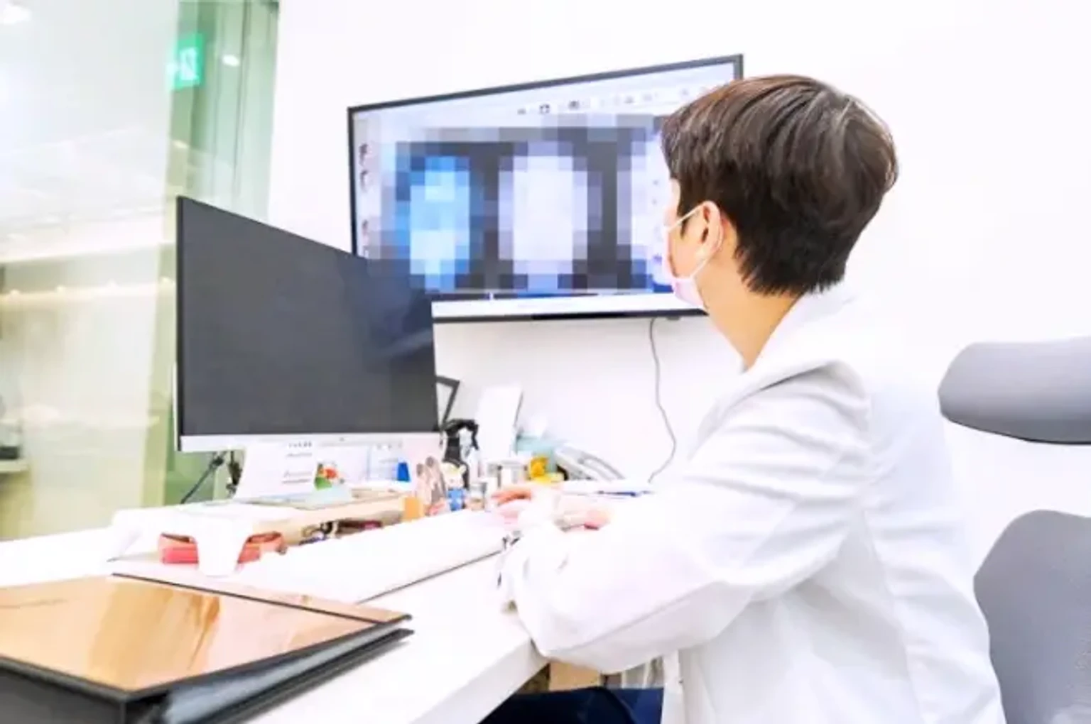 피부과 진료실에서 흰 가운을 입은 의료진이 컴퓨터 모니터에 표시된 피부 관련