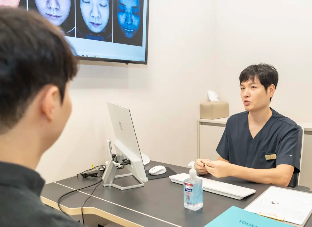 부평 유앤아이의원 진료실에서 피부 두께와 고민 부위를 정밀 진단 후 스킨부스터 시술 계획을 설명하는 의료진
