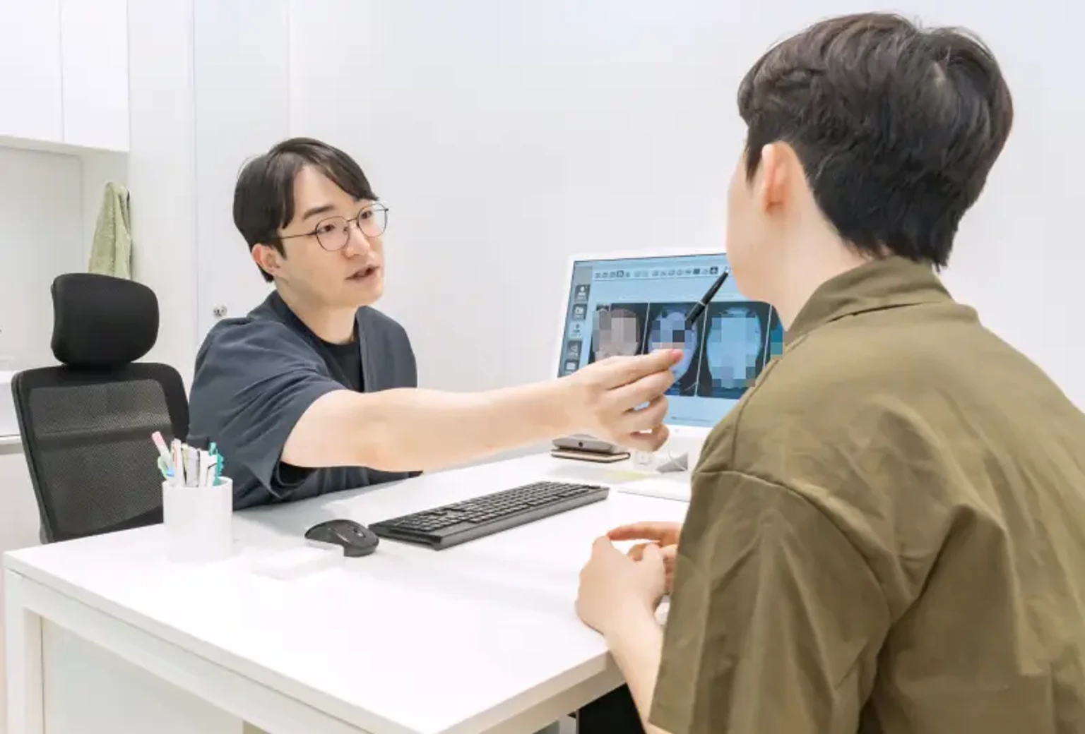 유앤아이의원 안산점에서 의료진이 환자에게 피부 상태를 설명하며 포텐자 팁 시술에 대해 상담하는 모습