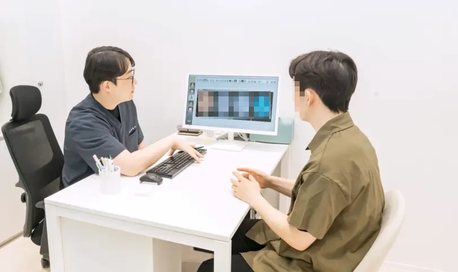 안산 유앤아이의원 진료실에서 의료진이 환자와 모니터를 보며 피부 상태와 리프팅 시술에 대해 상담하는 모습