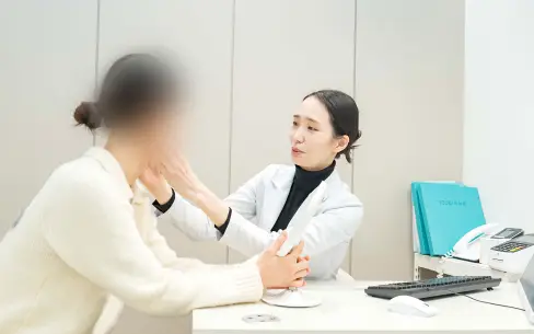 구로피부과 유앤아이의원 전한별 대표원장이 피부 상태를 확인하고 쥬베룩 볼륨 시술 계획을 설명하는 모습